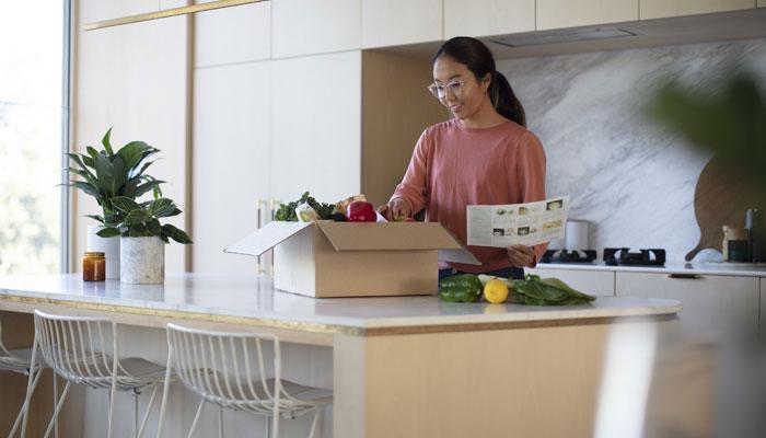 Lady unpacking a food delivery box in her kitchen